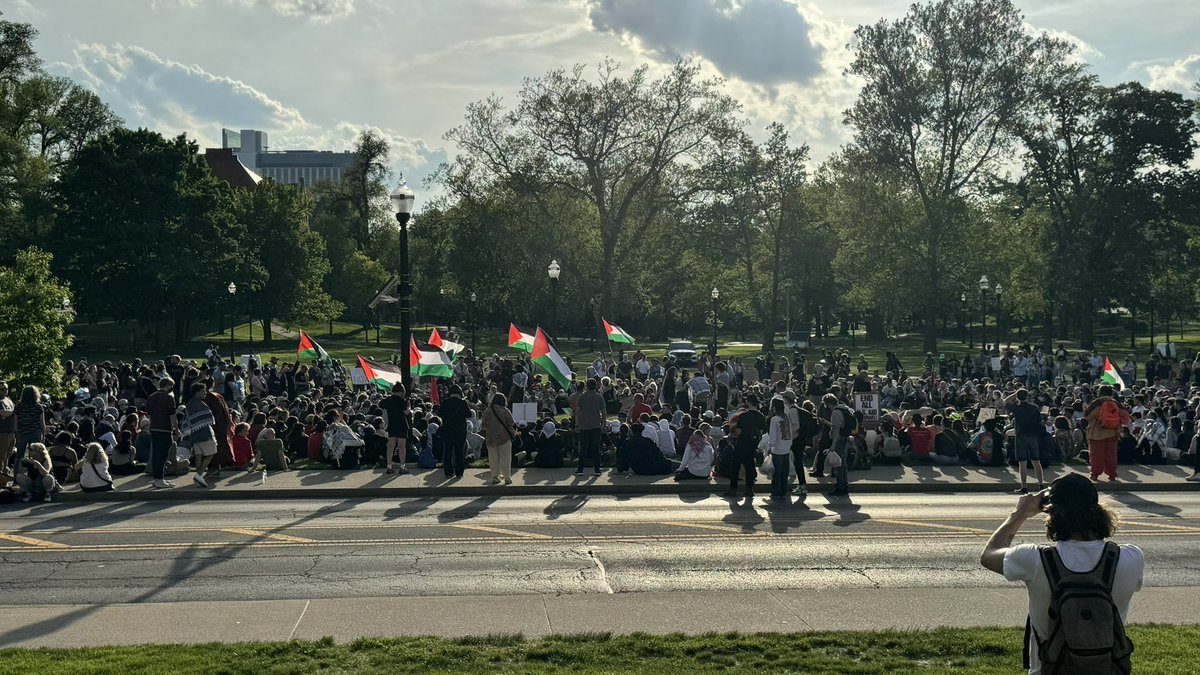 Upwards of 400 people are protesting the war in Gaza on the South Oval, also urging Ohio State to divest from Israel assets. Protestors are sitting in a square formation and chanting phrases, including 'The more they try to silence us, the louder we will be.'