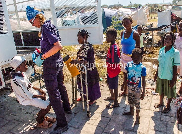 A US paramedic treats injured Haitians at a refugee camp in Port-au-Prince, Haiti. 2010. Gary Moore photo. Real World Photographs. #paramedic #women #haiti #earthquake #aid #portauprince  #injured #garymoorephotography #realworldphotographs #nikon #photojournalism #photography