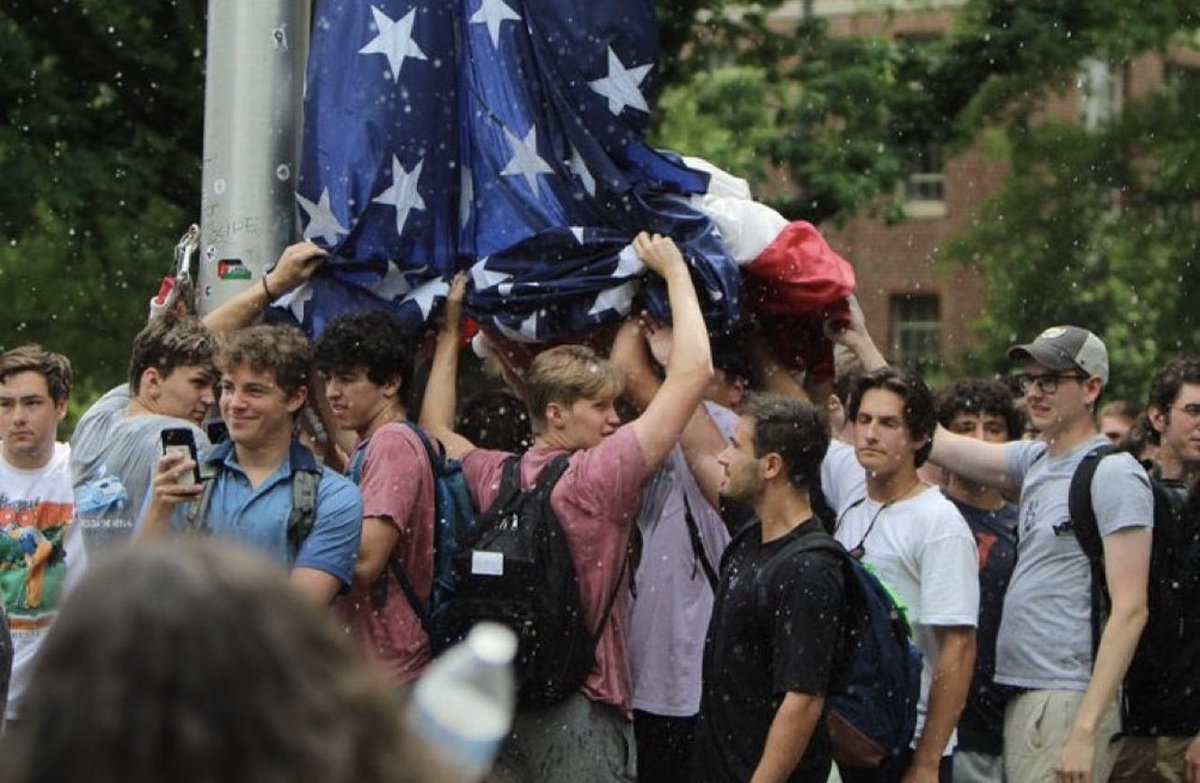 Photo of the year: Fraternity brothers are pelted by anti-Israel protesters at UNC Chapel Hill while protecting the United States flag as it is re-hoisted following its removal by protesters.