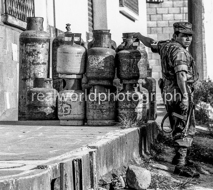 A Guatemalan soldier watches over a factory in the capital. Guatemala City, Guatemala. CA. 1992. Gary Moore photo. Real World Photographs. #guatemala #soldier #military #security #sweden #malmo #garymoorephotography #realworldphotographs #nikon #photojournalism #photography
