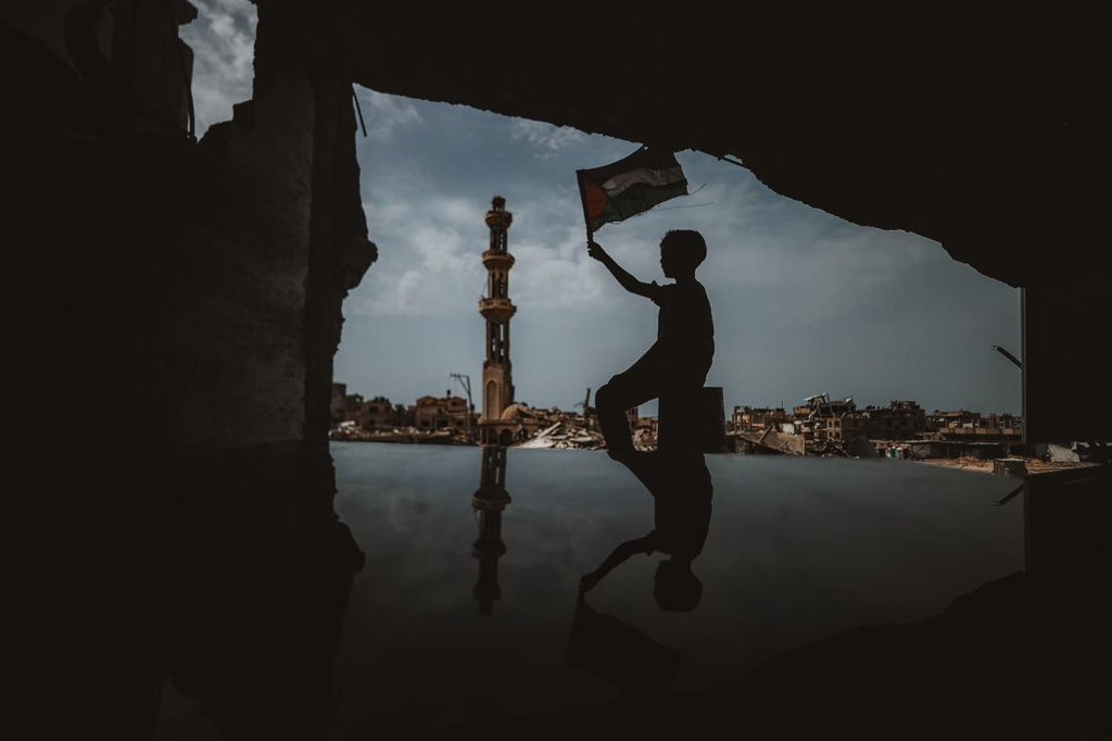 A Palestinian raises the Palestinian flag around of the wreckage of his house in Khan Yunis in the southern Gaza Strip. (Anadolu Ajansı - 📷Ali Jadallah)