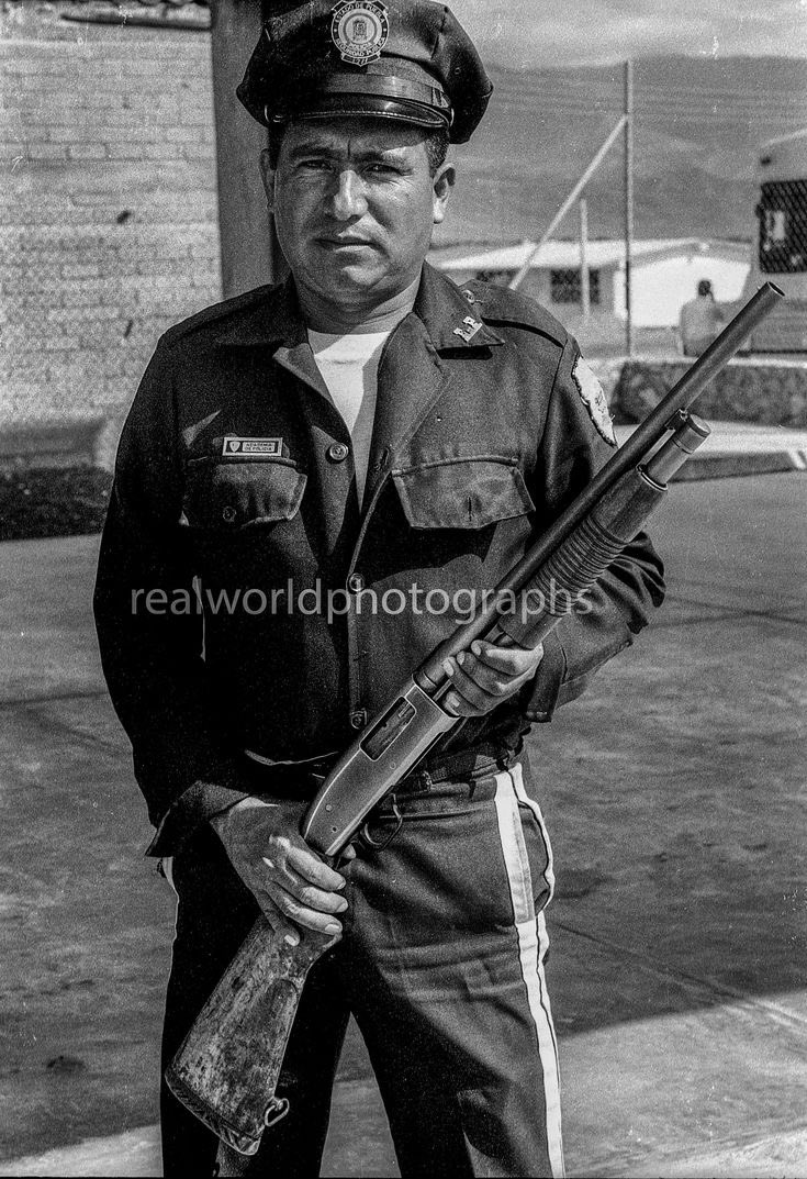 A police officer poses with his shotgun in Puebla, Mexico. 1992. Gary Moore photo. Real World Photographs. #police #mexico #shotgun #puebla #cop #safety #blackandwhitephotography #garymoorephotography #realworldphotographs #nikon #photojournalism #photography