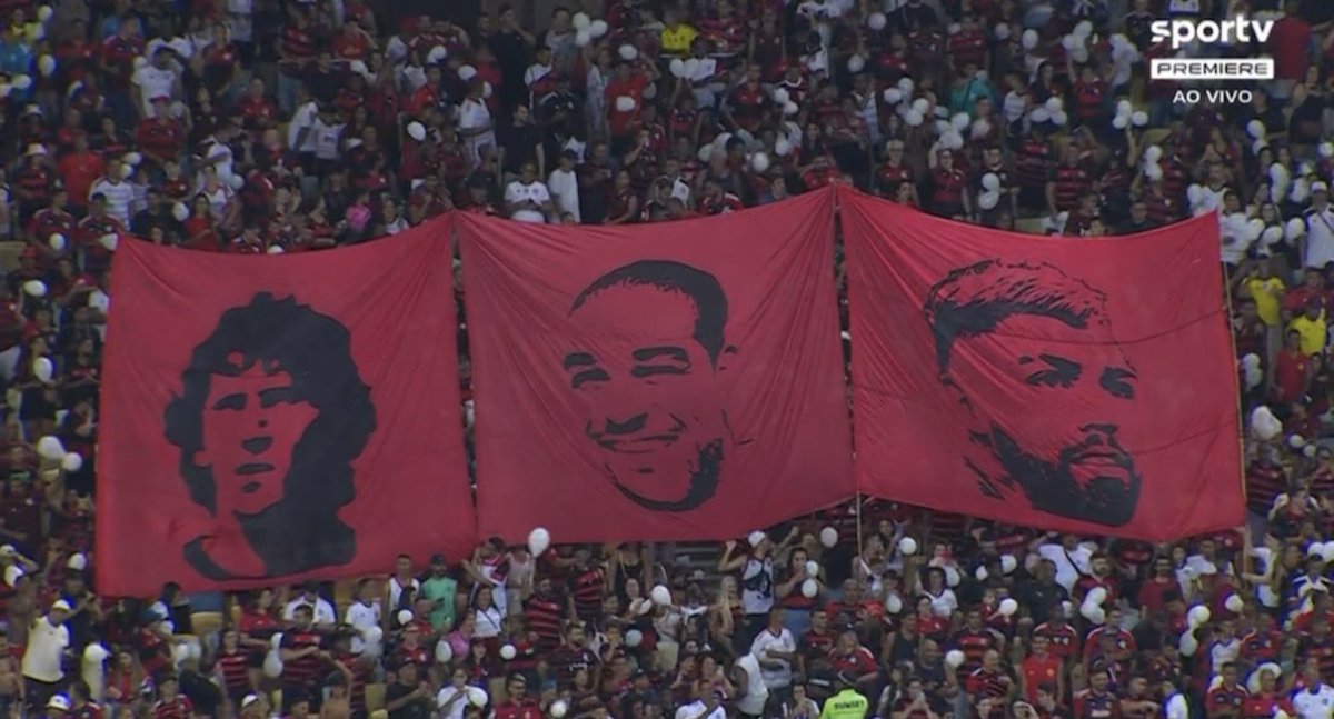 Torcida do Flamengo com bandeiras de Zico, Adriano e Gabigol no Maracanã.

📸 Reprodução/SporTV/Premiere