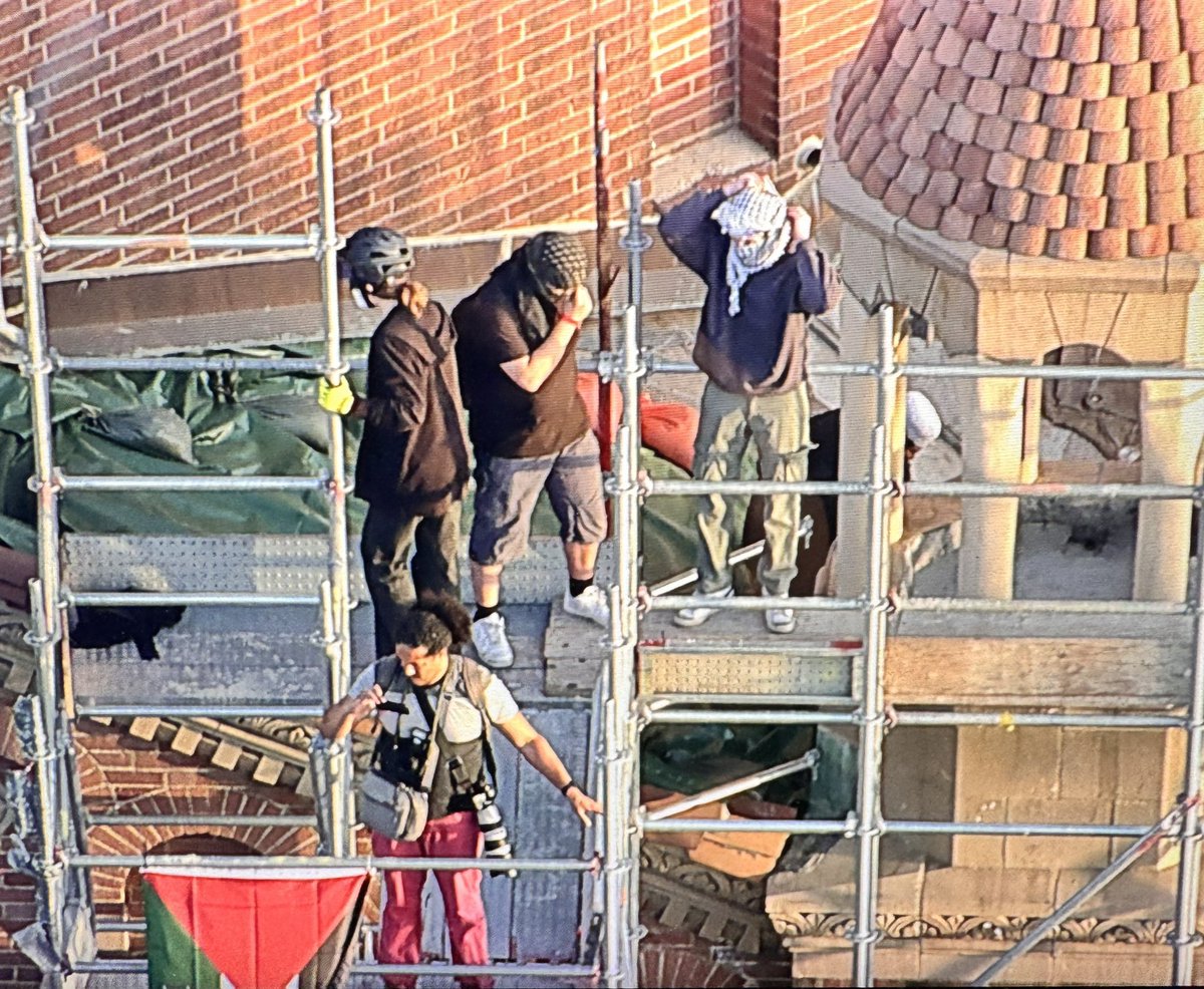 DEVELOPING: Individuals are now climbing scaffolding up to the steeple atop the Powell Library.
