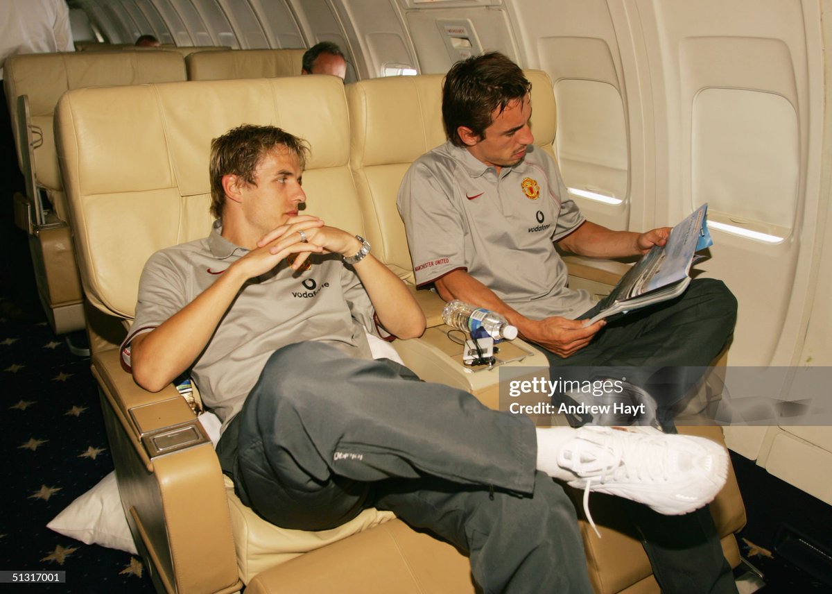 Phil and Gary Neville of Manchester United relax aboard the Manchester United aeroplane, as they fly to the second match of their US tour (2004)