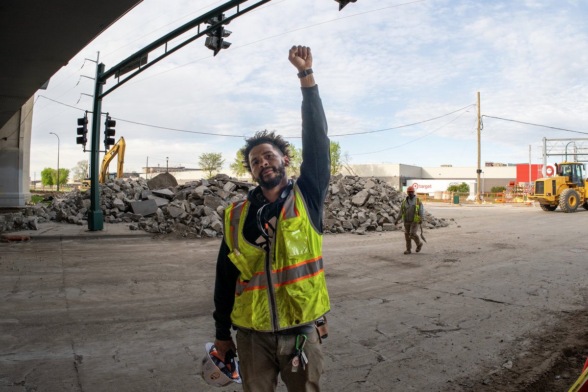A worker puts his fist up in solidarity as the International Workers Day march passes by on Lake Street in Minneapolis. May 1, 2024.