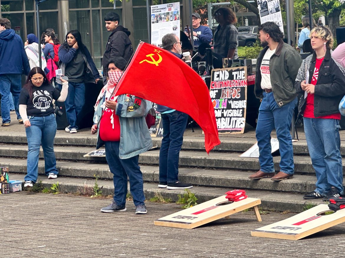 A heavy set person waves a communist flag at the far-left May Day protest outside the Oregon state capitol. Photo by @hunnybadgermom: