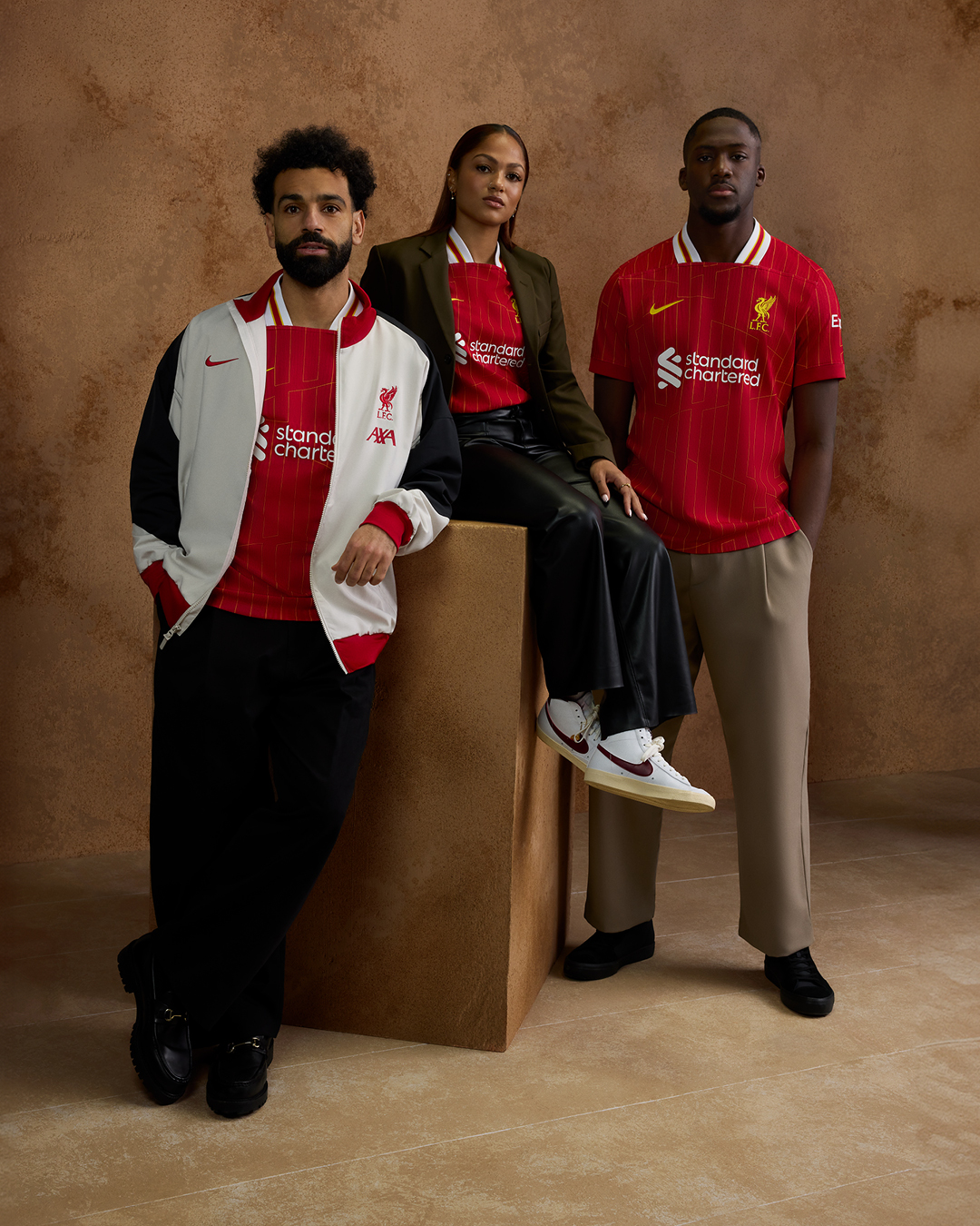 Mohamed Salah, Taylor Hinds and Ibrahima Konate model the new 2024/25 home kit and anthem jacket.

The red jersey features a chrome yellow pattern design which sees a modernised take on the legendary '84 home shirt, a season which saw the Reds become European Champions for the 4th time in Rome and the first English Club to win a Treble of major honours.