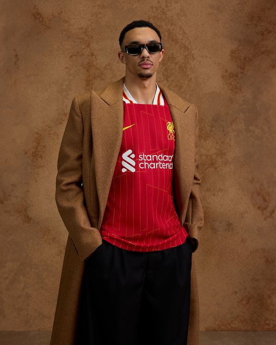 Trent Alexander-Arnold poses in our new 2024/25 home kit. 

The red jersey features a chrome yellow pattern design which sees a modernised take on the legendary '84 home shirt, a season which saw the Reds become European Champions for the 4th time in Rome and the first English Club to win a Treble of major honours.