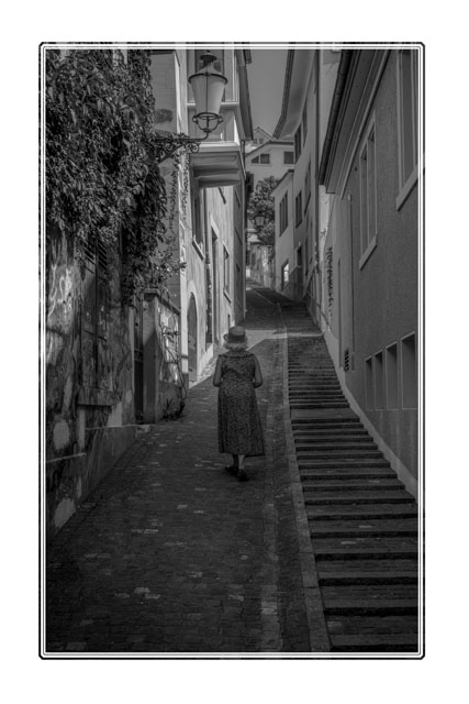 A #woman takes a #peaceful #stroll on a hot #summer day to #explore one of the narrow side #streets in the #historic #oldtown of #Salzburg, #austria. For more #images like this, go to darrensmith.org.uk. #travelphotography #blackandwhitephotography #architecturephotography