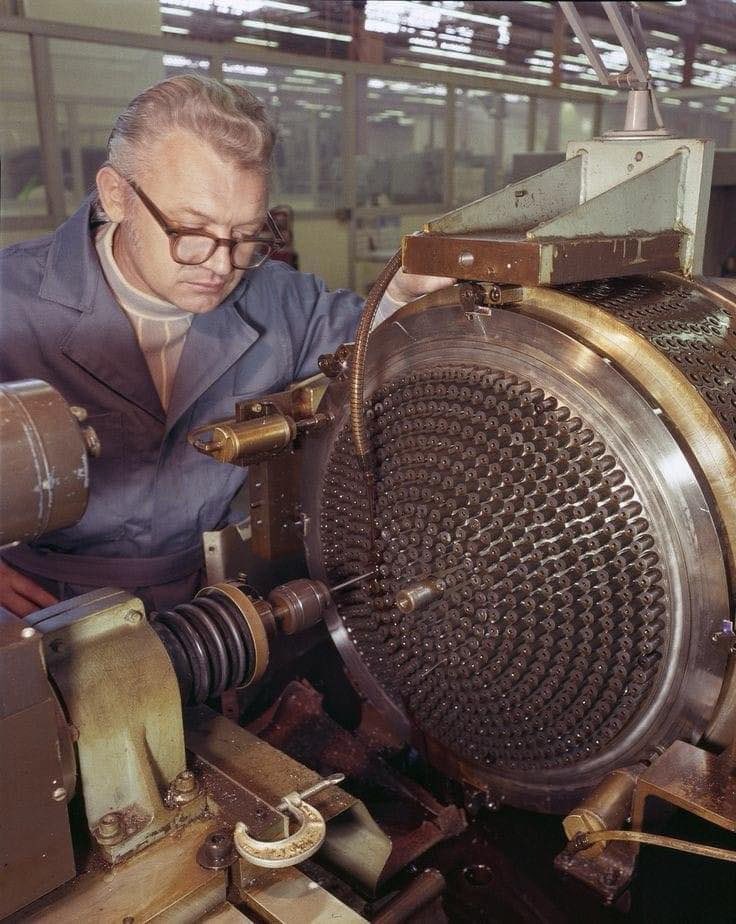 A machinist working on a Space Shuttle main engine injector in 1977