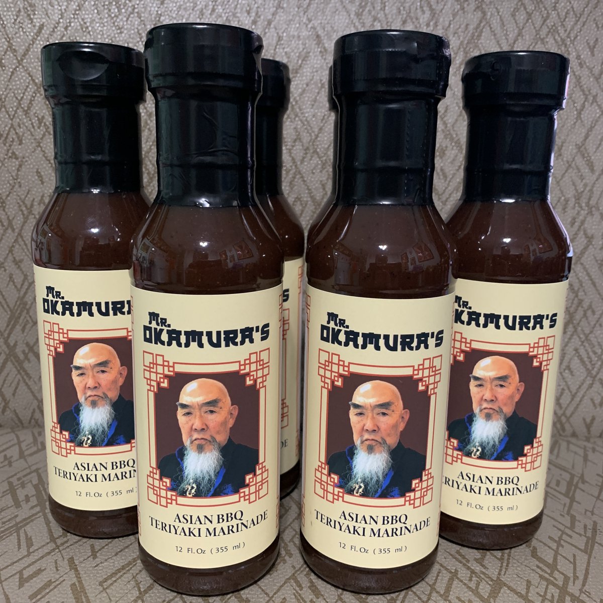 Available at geraldokamura.com/fan-club/ Mr. Okamura’s Asian BBQ, Teriyaki Marinade ,entwines the umami-rich flavors of soy sauce, ginger, and garlic with the subtle heat of cayenne chiles and the robust essence of molasses, creating a marinade that elevates any dish it touches.