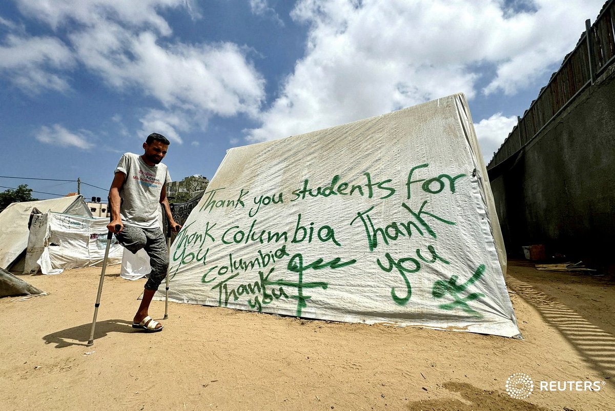 A man uses crutches next to a tent sprayed with a message thanking pro-#Palestinian #university students who are protesting for their support, in #Rafah in the southern #Gaza Strip, REUTERS/Mohammed Salem TPX IMAGES OF THE DAY #USA_Universities