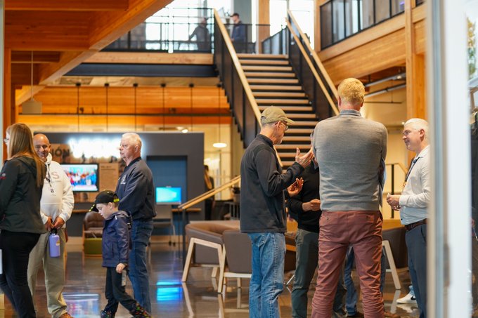 Visitors stand in reception/greeting area at new district office with staircase in background leading to upper level