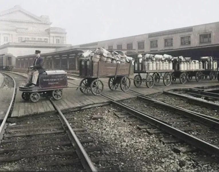 A colorized update of a 1920 photo showing Wells Fargo Express carts crossing the tracks at Union Station.