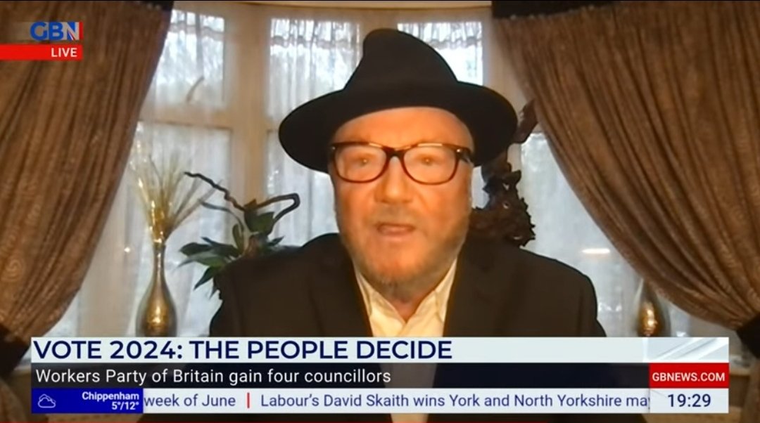 George Galloway seems to be wearing a bowler in his front room