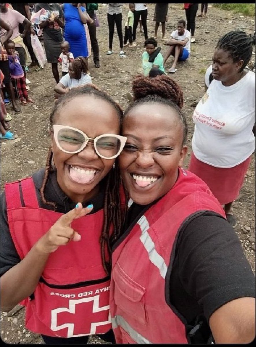 Kenya Red Cross employees take a selfie smiling in front of distressed flood victims.