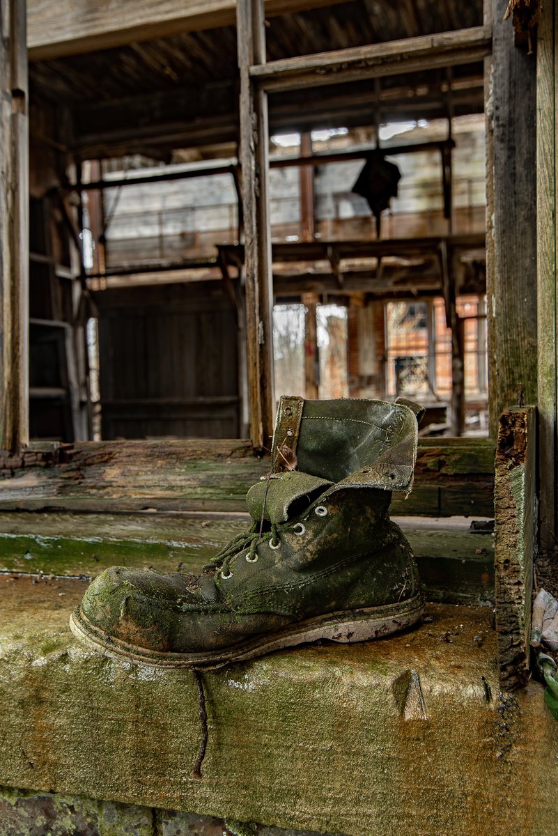 An old work boot, green with moss, sits upon a windowsill inside an abandoned rubber factory in Youngstown, Ohio.