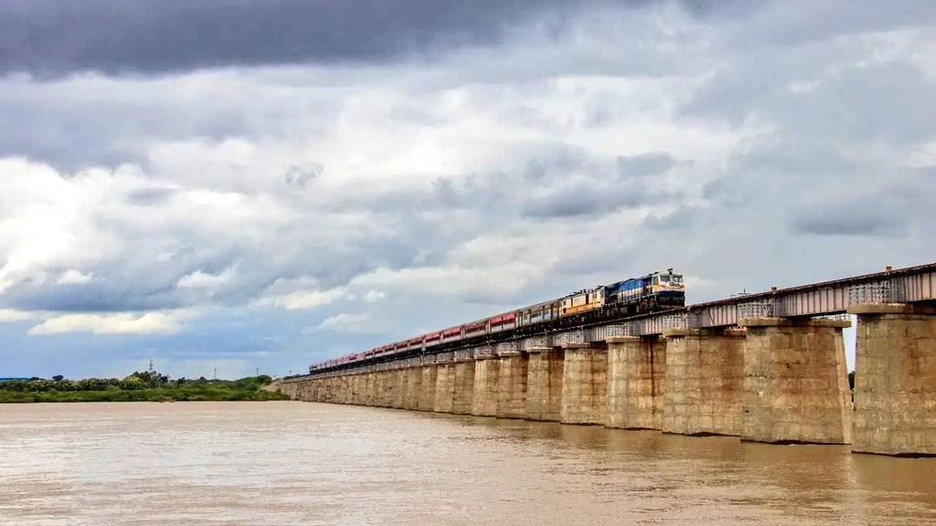 Today's #railway #photo - the capture of trains passing over a bridge with the river in full flow and dark clouds in the background is so beautiful - near Kurnool station in the jurisdiction of @drmhyb in @SCRailwayIndia! Pic courtesy, late Prithvi Raj! #IndianRailways @baxirahul