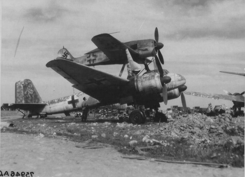 Müttefikler, ele geçirilen bir Mistel 'uçan bomba'yı inceliyor. Focke-Wulf Fw-190, Junkers Ju-88 bombardıman uçağının üstüne yerleştirilmiş. Plana göre bombardıman uçağı patlayıcılarla doldurulacak ve avcı pilotu tarafından kontrol edilecekti, Fransa, 4 Mayıs 1945. #tarihtebugün