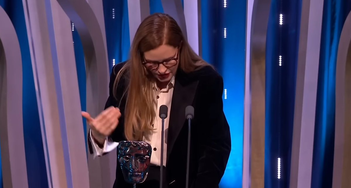 the category is Justine Triet wearing glasses while giving acceptance speeches