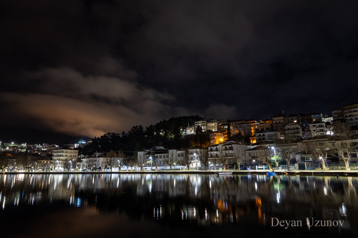 Kastoria's Dreamy Waters Beneath the veil of night, Kastoria unveils its mystical charm, casting an enchanting spell upon all who behold its beauty. In this captivating shot, the city's twinkling lights dance upon the tranquil surface of the lake.