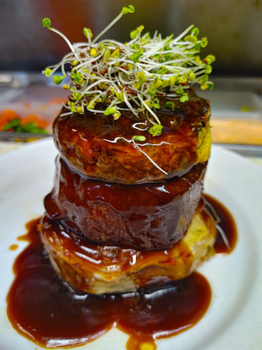 Beef tenderloin with spinach soufflé on Au gratin potatoes and covered with a brandy demiglace and broccoli micro greens.