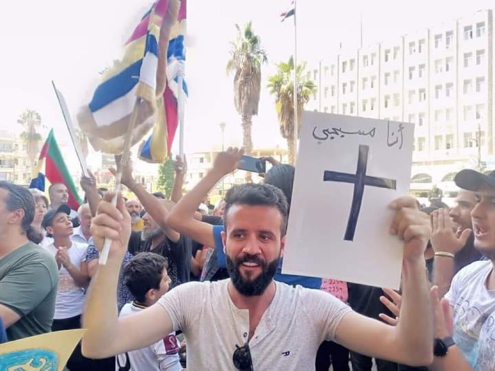 A Syrian Christian raises the Druze flag.