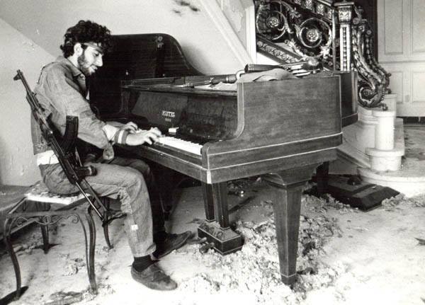 A Lebanese fighter plays the piano in a house his forces have recently taken over during the 1975-90 civil war. 🇱🇧