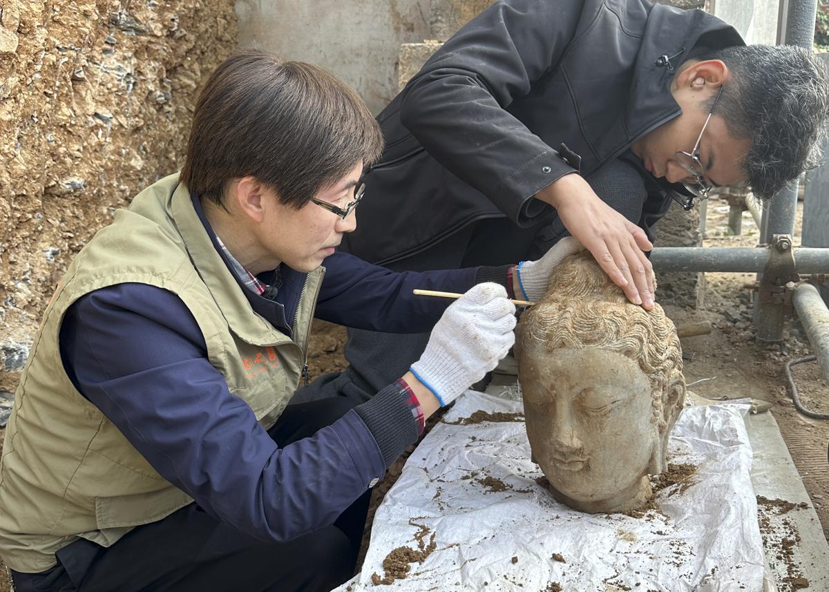 Archaeologists clean a stone Buddha head that was discovered at the Leigutai caves of the Longmen Grottoes in Luoyang, Henan province News article in comments section