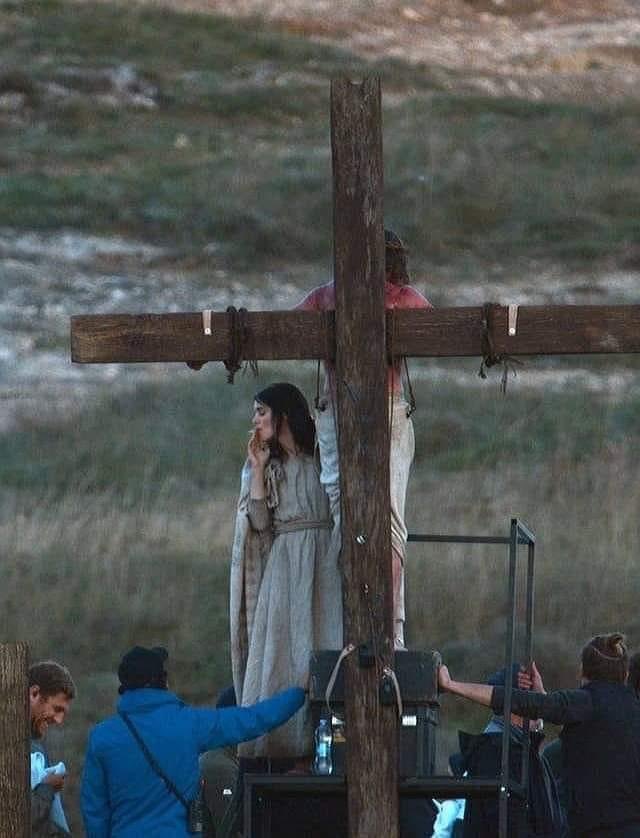 Rooney Mara as Mary Magdalene smoking a cigarette while Jesus (Joaquin Phoenix) is crucified.