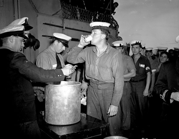 Splicing the mainbrace: Ordinary Seaman Ernest Weir receives an extra rum ration during Victory over Japan celebrations aboard HMCS PRINCE ROBERT, Sydney, Australia, 16 August 1945 (LAC a166428-v6) #RCN #History