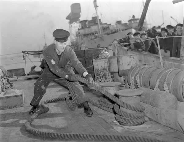 An unidentified rating aboard an unidentified ship of the Royal Canadian Navy tightening a mooring line around a bollard, H.M.C. Dockyard, Halifax, Nova Scotia, Canada, 3 March 1943. (LAC a107198-v6) #RCN #History