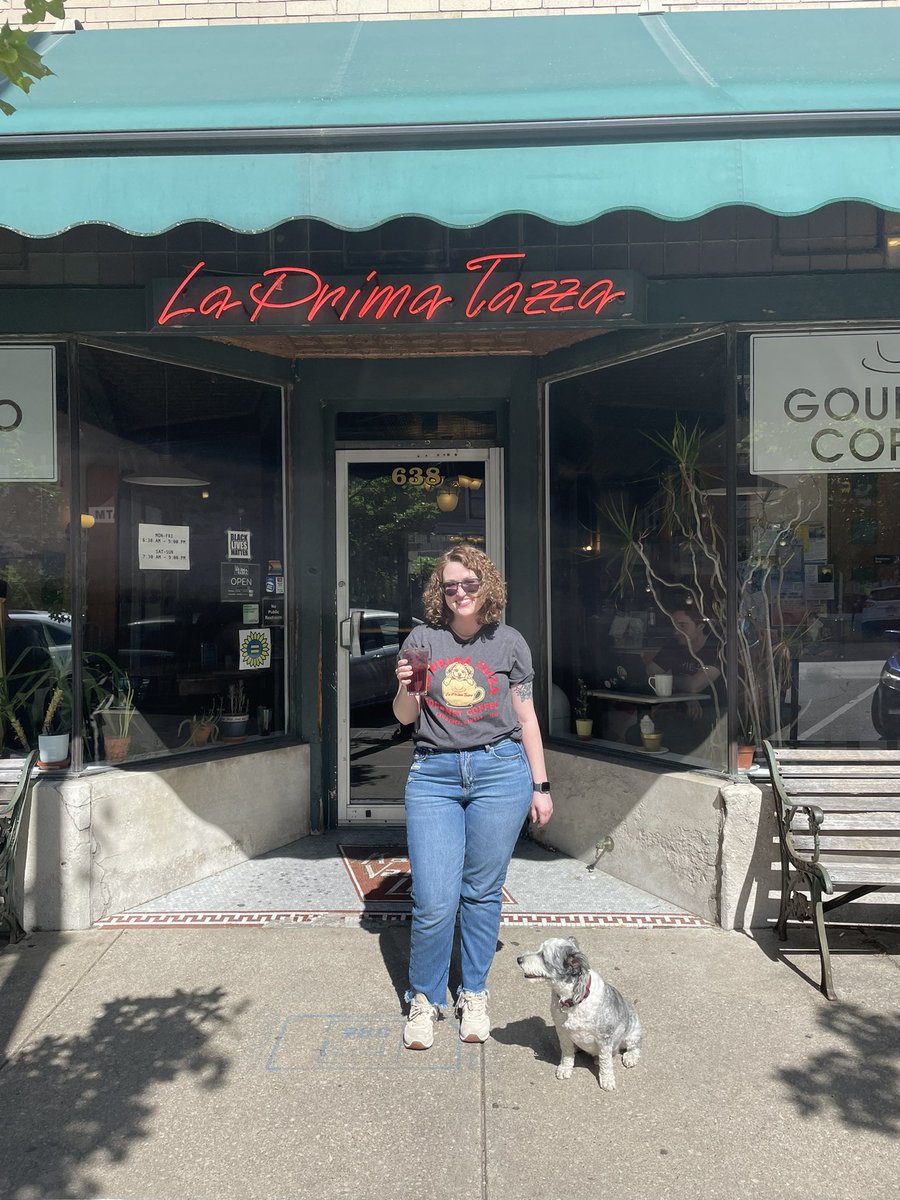 Whew! It’s gonna be a hot day in Lawrence! Stop by @La_Prima_Tazza for an iced coffee or an Italian soda to cool down, and check out their new t-shirt featuring the most adorable coffee shop dog in the world ☕️