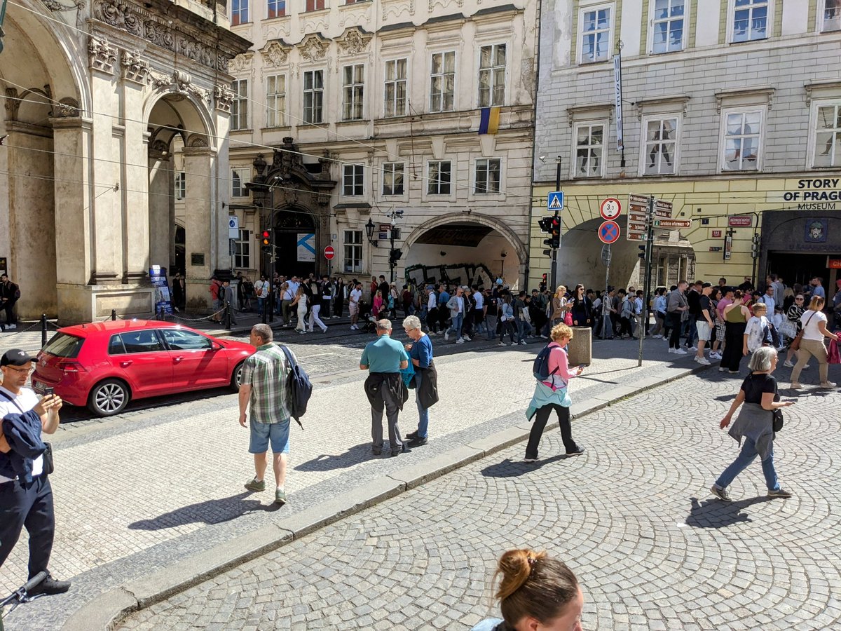 Desítky, ne-li víc než sto lidí, vs pár lidí v autě. Kontrasty dopravy v centru památkové rezervace.