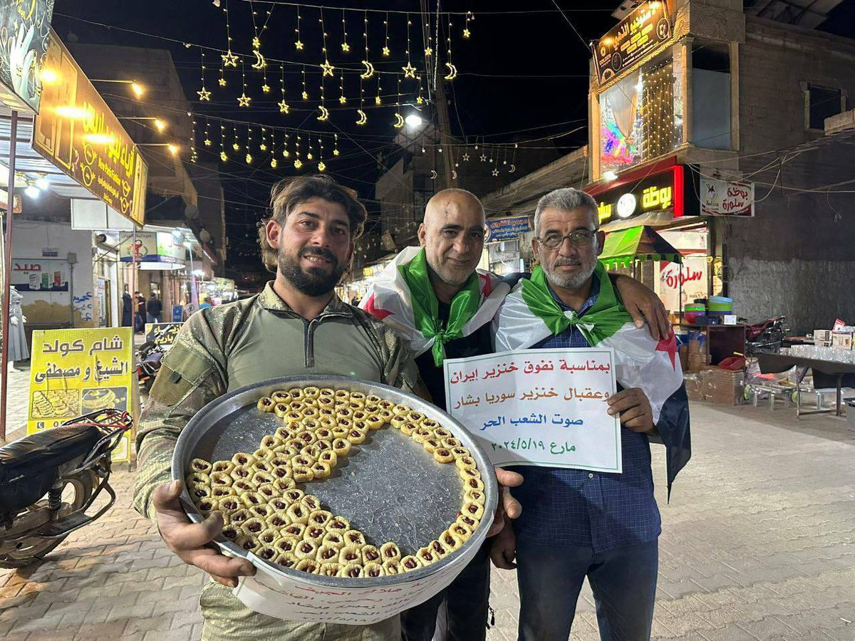 Free Syrians in northern Aleppo are passing out baklava in celebration of Iranian President Raisi's helicopter crash. They're holding a sign that wishes the same fate onto Bashar al-Assad.
