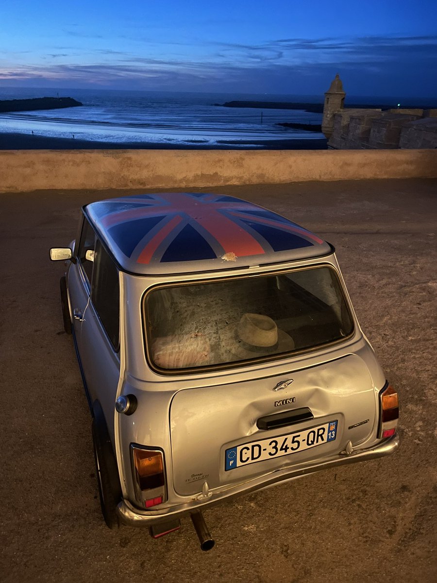 This is a cool looking car with a French tag and a British flag sign on top parked near the local beach in Morocco