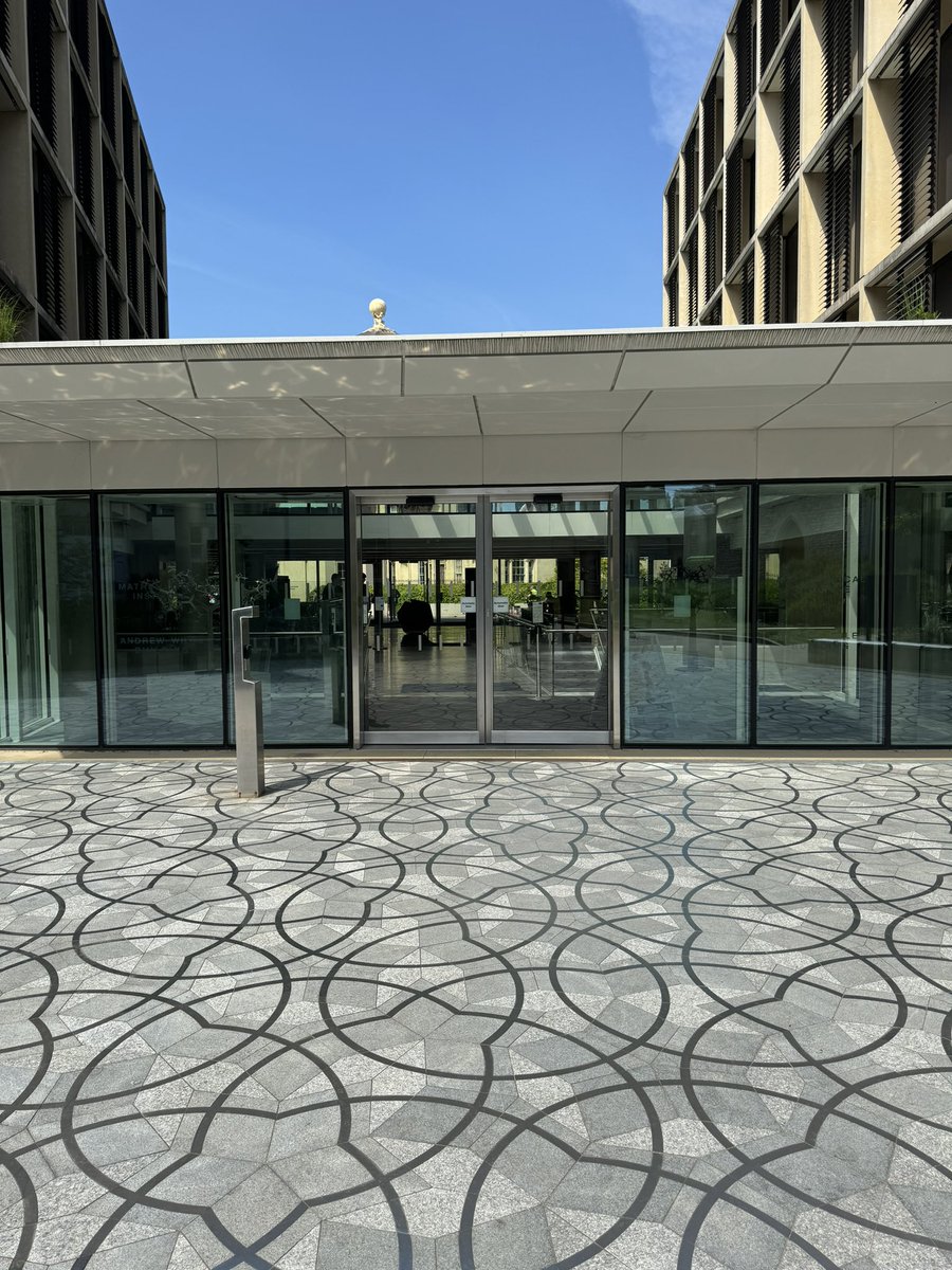 The Penrose tiling basks mathematically in the Oxford spring sunshine, reflecting against the entrance roof of our building while, above, Atlas and Hercules hold up the world.