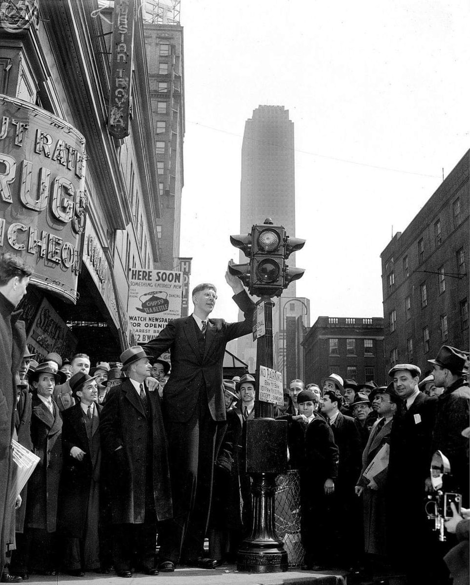 8ft 11.1in (2.72m) tall Robert Wadlow surrounded by people as he leans on a traffic light in New York City in 1937