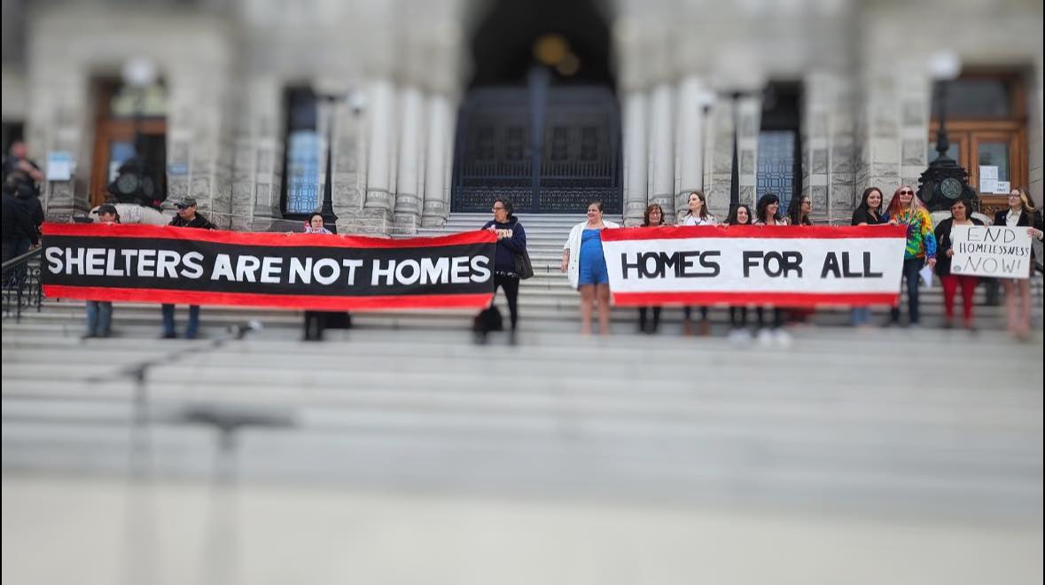 Check out this photo of two protest banners revealed on the front steps of the BC Legislature building from May 7, 2024 that say : #SHELTERSARENOTHOMES #HOMESFORALL