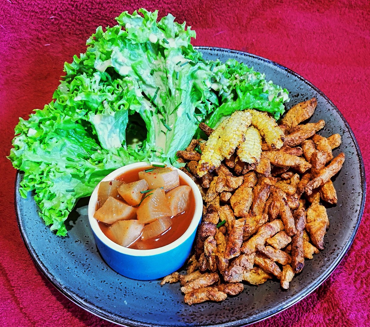 Geröstete Sojaschnetzel ala Hühnerhaut, geröstete Maiskölbchen, pikant eingelegter Kohlrabi und Salat mit Dressing.