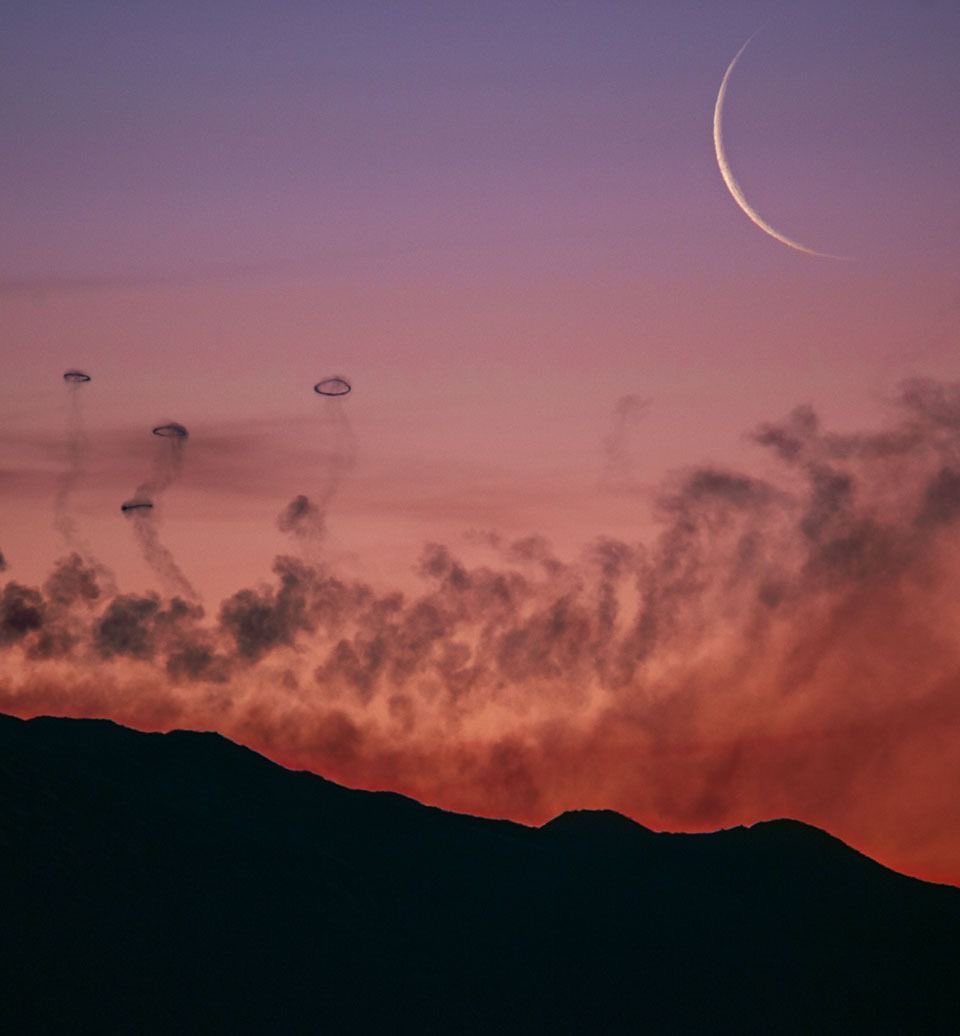 this picture is a work of art - the moon above volcanic smoke rings