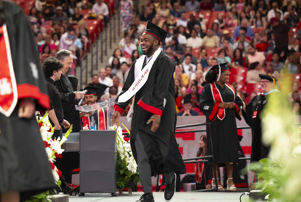 Graduate with a big smile skips across stage with a stoke that says “Athlete”