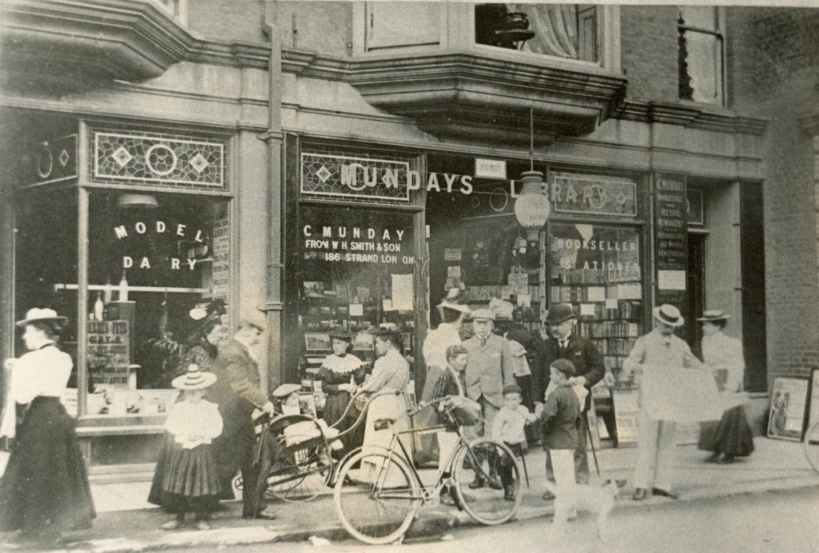 View taken outside Charles Munday's Bookshop, Strand House, Church Street, #Cromer. The pavement is busy with people, a perambulator and bicycle. 1897.
