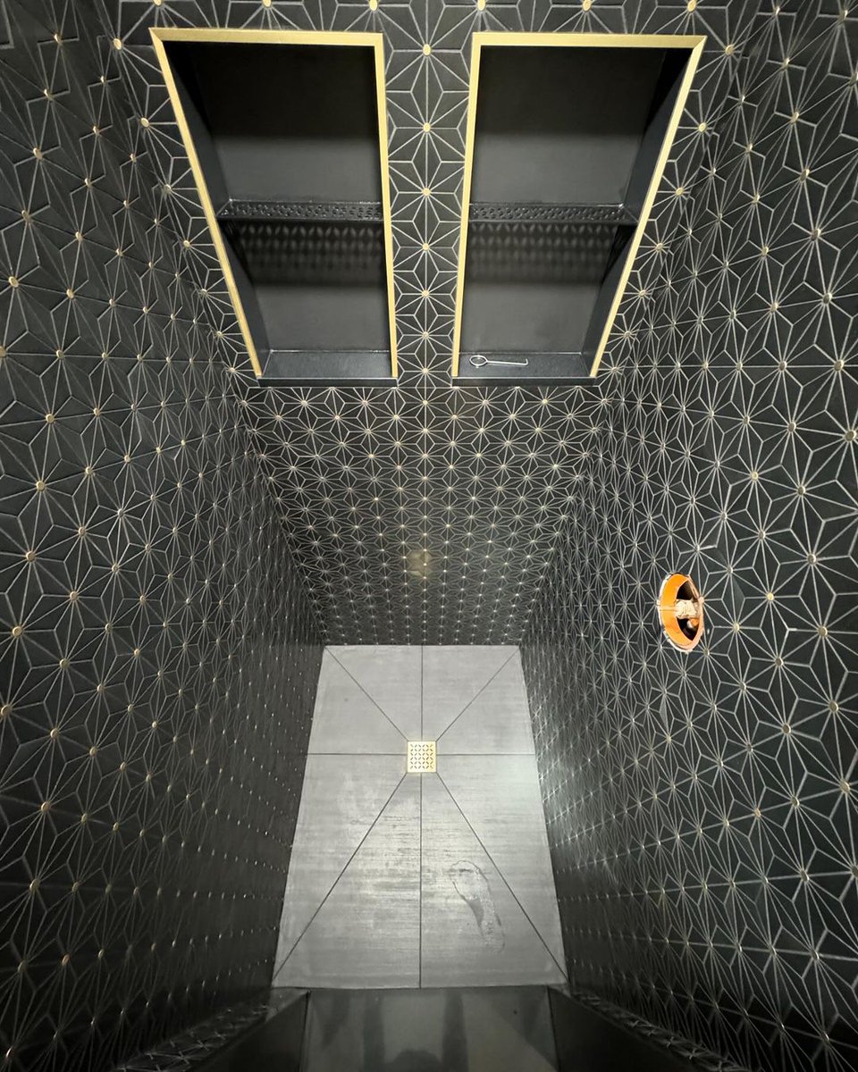Elegance in every detail with this stunning black and gold shower. Shoutout to M Ramos Tile for turning this small shower into a true masterpiece using the works from Schluter: Kerdi-Board, Kerdi membrane, a STYLE drain, niche, shelf, and profiles. #schluter #tileshower