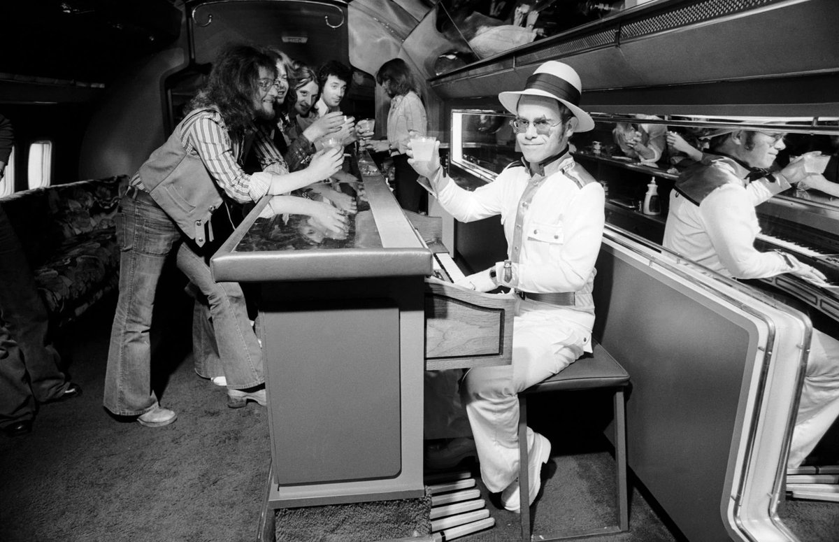 Elton John travelling on his private jet with a piano bar, 1974