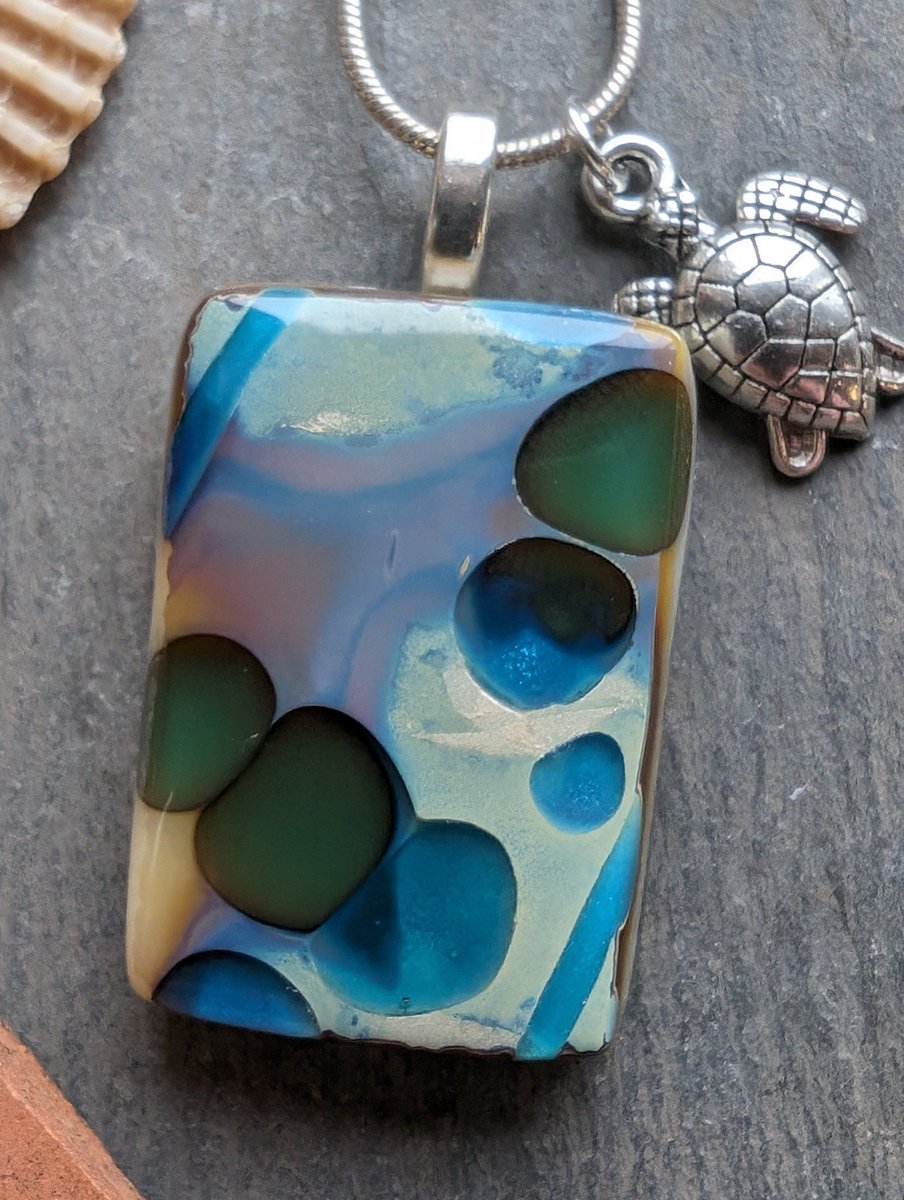 A unique beach and sea inspired fused glass necklace. Lovely pools of green and blue within this special reactive glass necklace. #handmade #etsy #giftideas #shopindie buff.ly/4ag5s8Y