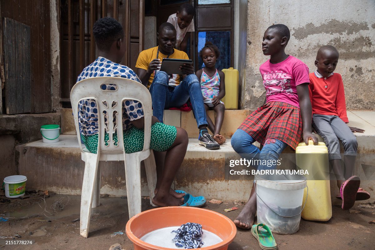 A Uganda Bureau of Statistics (UBOS) census enumerator gathers data from the members of a family during the National Housing and Population Census in the Kamwokya informal settlement of Kampala, on May 10, 2024.