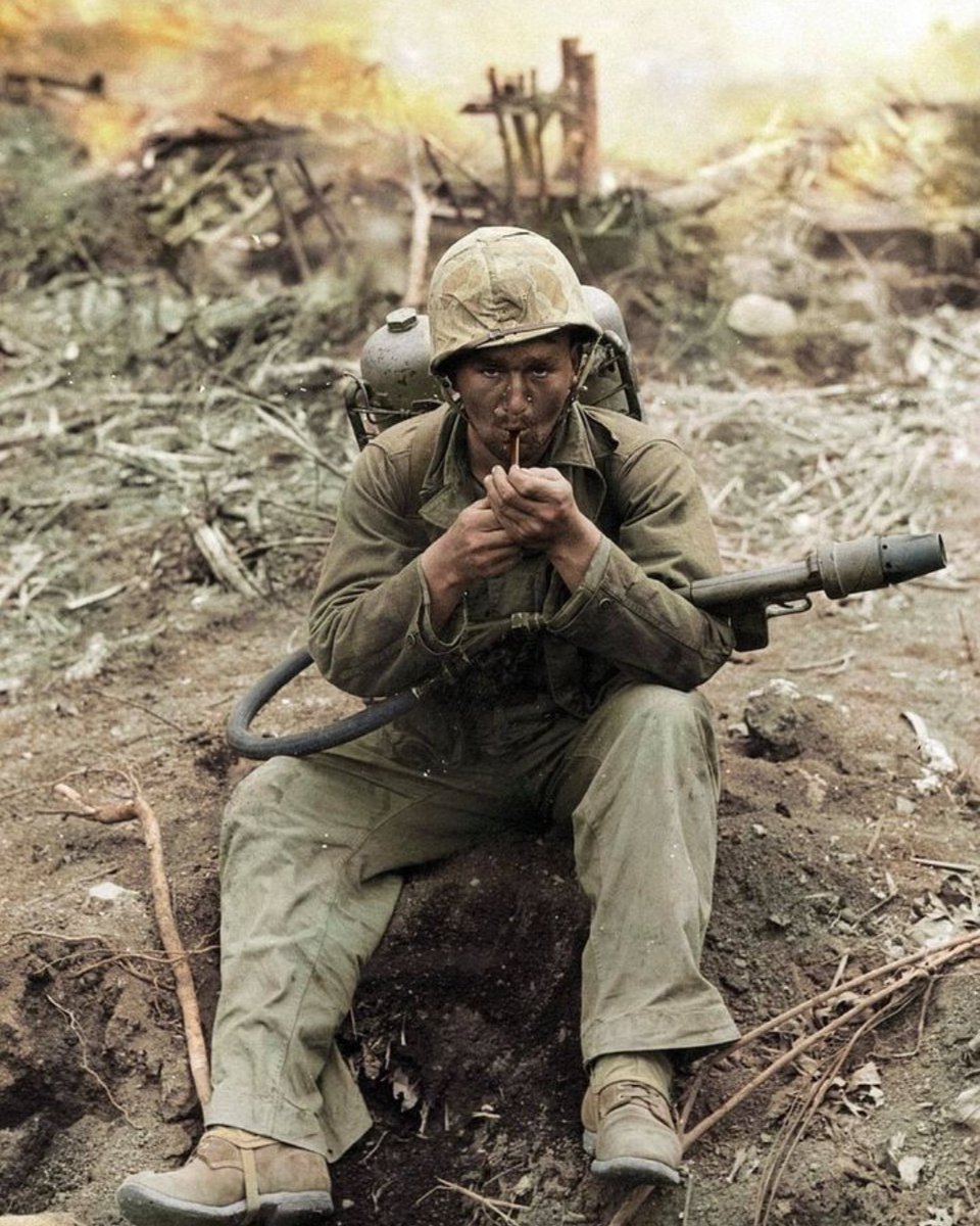 A U.S. Marine with an M2-2 flamethrower strapped to his back stops to light his pipe during a break in the fighting on the island of Iwo Jima in February, 1945. #History #WWII
