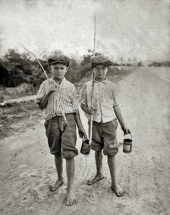 Two boys with cane poles and bait worms in cans headed to the local fishing hole somewhere in Texas early 1900’s.👍👍👍👍